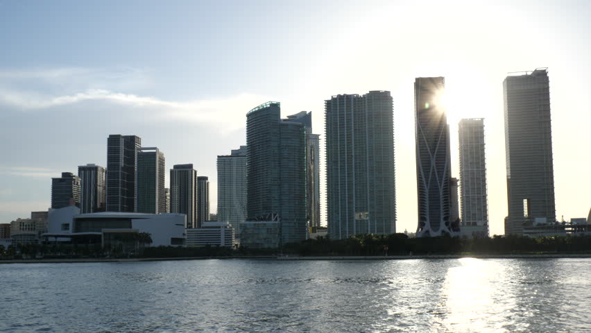 The sun gleams between buildings as we pass along the Miami skyline by boat near sunset.