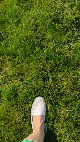Concept video of nicely dressed woman walking on green grass, giving the ideas of taking one step at a time,  taking a stroll, stepping out boldly, or putting your best foot forward.
