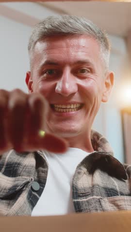 Happy man unpacking delivery parcel at home. View inside from the box. Smiling satisfied young guy shopper, online shop customer opening cardboard box receiving purchase gift by fast postal shipping.