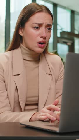 Caucasian young businesswoman girl using laptop notebook typing browsing, loses receive lottery results, bad news loss, fail, computer virus error in modern office lobby. Lady sitting in hotel hall