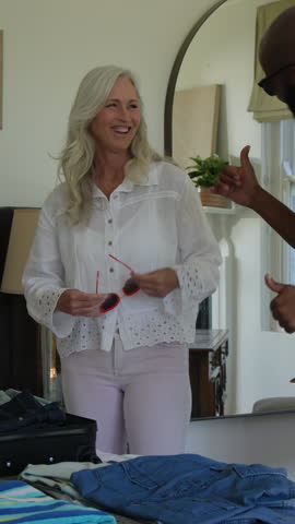 Vertical video: Opening suitcase, couple folding shirts and packing passport for trip in bedroom. Travel, packing, couple, leisure, lifestyle, organized, vertical video