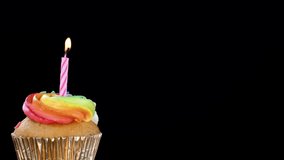 Rainbow-frosted cupcake with extinguished pink candle and swirling smoke on black background, close-up. - Powered by Shutterstock - Get 15% off with code: PIKWIZARD15