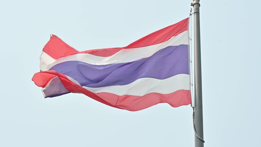 A Thailand national flag blowing by wind against the sky. The Thai flag, known as the "Tri-Rong" or tricolor.