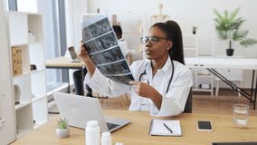 Young African American female doctor examining X-ray scan in modern medical office beside male colleague working. Represents professional healthcare, diagnosis, collaborative environment. - Powered by Shutterstock - Get 15% off with code: PIKWIZARD15