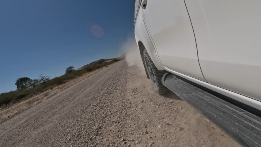 Close-up of a car wheel driving on a gravel road in Africa.