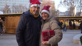 Warmly dressed senior couple exchanging heartfelt christmas presents, sharing festive joy and love at traditional christmas market during winter season - Powered by Shutterstock - Get 15% off with code: PIKWIZARD15