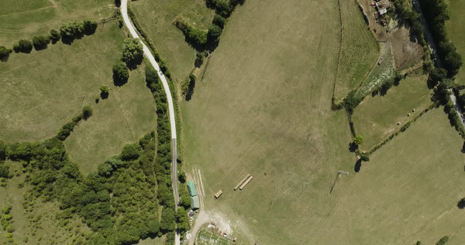Aerial view of roads cutting through green fields and buildings with terracotta roofs, creating a patchwork of textures, Pescocostanzo, Abruzzo, Italy.