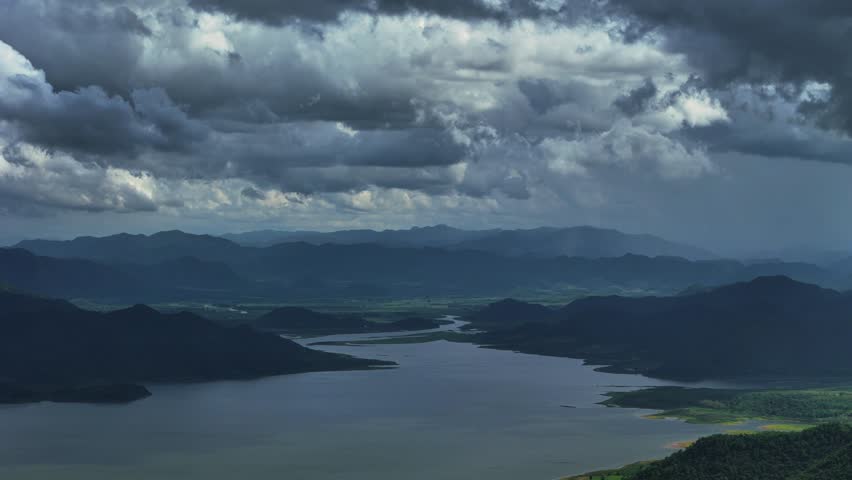 Moody mountain lake view with layered hills under heavy cloud cover
