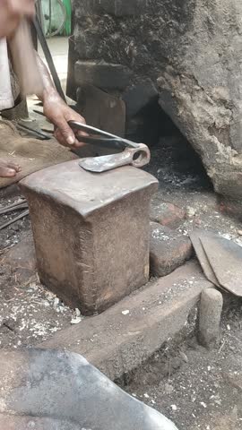 Traditional Indian Blacksmith Forging Hot Iron on Anvil with Hammer in Village Workshop