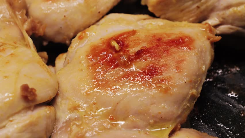 Chicken thighs cooked in a frying pan with aromatic spices. Cooking at home. High quality 4k footage
