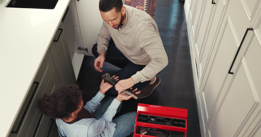High five, above and toolbox with father and daughter in kitchen for bonding, support and plumbing. Handyman, pipe maintenance and teaching with man and girl in family house for fixing together