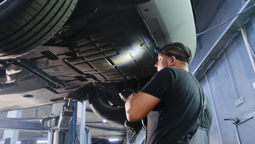 Mechanic holding impact wrench working on car wheel. Technician uses special tool to secure wheel to hub analysing degree of tightening