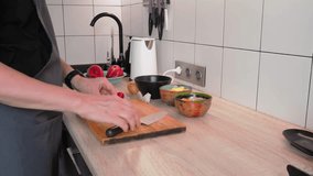 Chopping fresh vegetables in a sleek kitchen setup. Colorful bowls filled with ingredients are ready while a chef showcases proper knife skills on a wooden cutting board - Powered by Shutterstock - Get 15% off with code: PIKWIZARD15