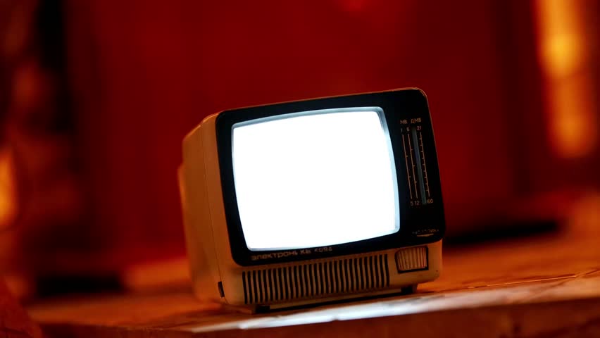 Old vintage television with blank screen glowing in dark room.