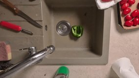 Washing green bell pepper under running tap water in kitchen sink. Food preparation process with cherry tomatoes nearby - Powered by Shutterstock - Get 15% off with code: PIKWIZARD15