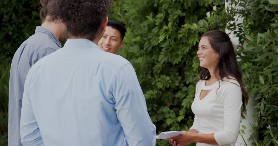 Female bride unfolding envelope and reading vows and exchanging ring on groom's finger at garden. Romance, celebration, commitment, elegance, happiness, outdoor, serenity