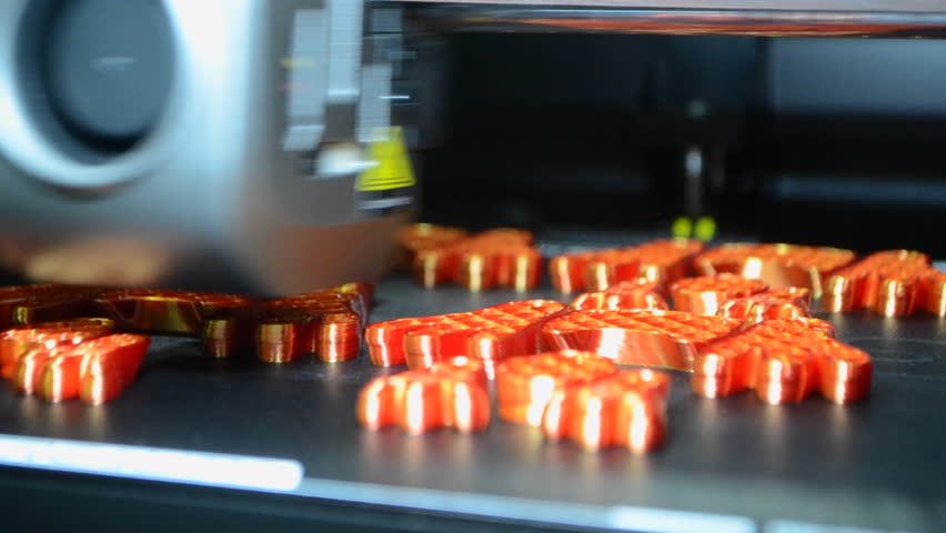 3D printer close up. Working 3D printer in process of printing object from molten orange plastic. 3D printer creating model by flowing liquid plastic from extruder of printer. 3D printing technology