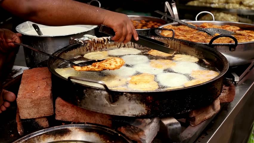 Cooking indian street food with oil and tongs in frame