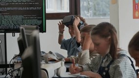 Modern schoolboy putting on virtual reality headset and watching presentation of augmented project while sitting by desk in front of computer monitor among his classmates at lesson - Powered by Shutterstock - Get 15% off with code: PIKWIZARD15