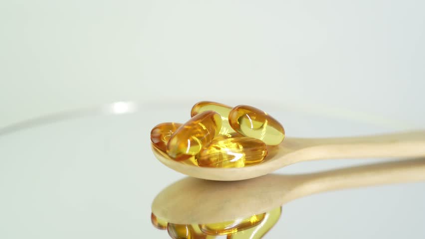 Vitamin capsules in wooden spoon, soft gels, Fish oil capsules, omega 3, oval gelatin, vitamin E