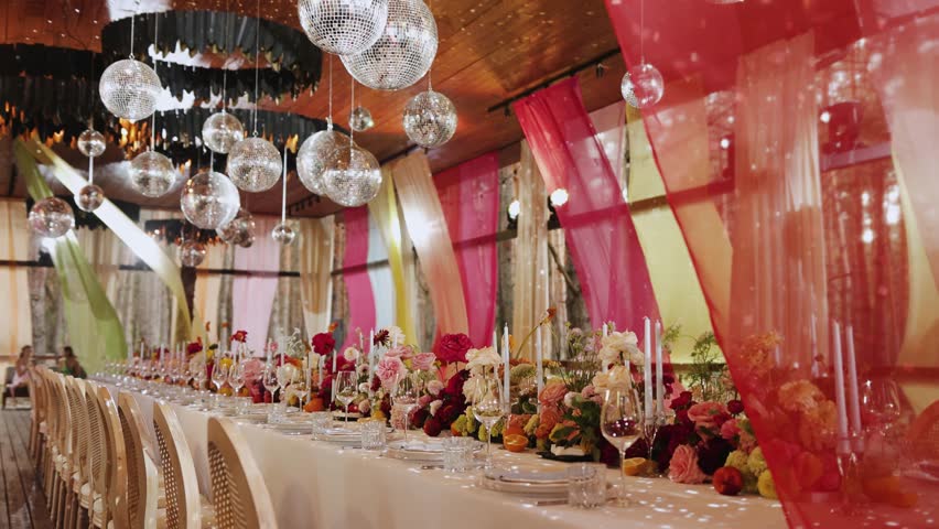 Wedding decor, glass, flowers, candles. A decorated dining table with colorful curtains and decor, as well as disco balls, is perfect for special events and gatherings.