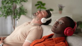 Interracial couple relaxing on sofa listening to music - Powered by Shutterstock - Get 15% off with code: PIKWIZARD15