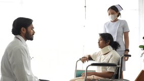 An orthopedic surgeon and a registered nurse assess a trauma patient with a potential cervical spine injury. The patient is immobilized in a cervical collar and wheelchair for evaluation. - Powered by Shutterstock - Get 15% off with code: PIKWIZARD15