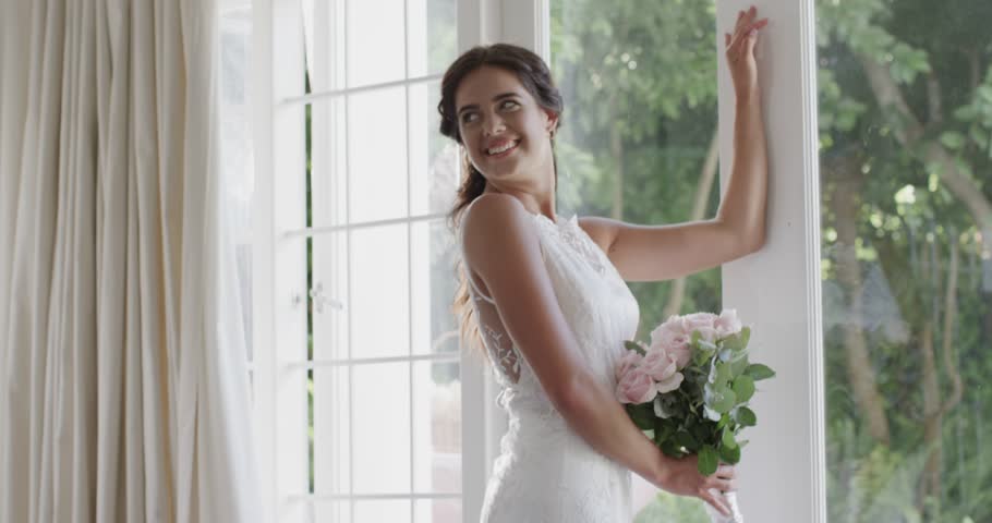 Bride and photographer entering suite showing DSLR images causing bride holding roses laughing. Wedding, intimate, candid, natural, joyful, professional, light-filled