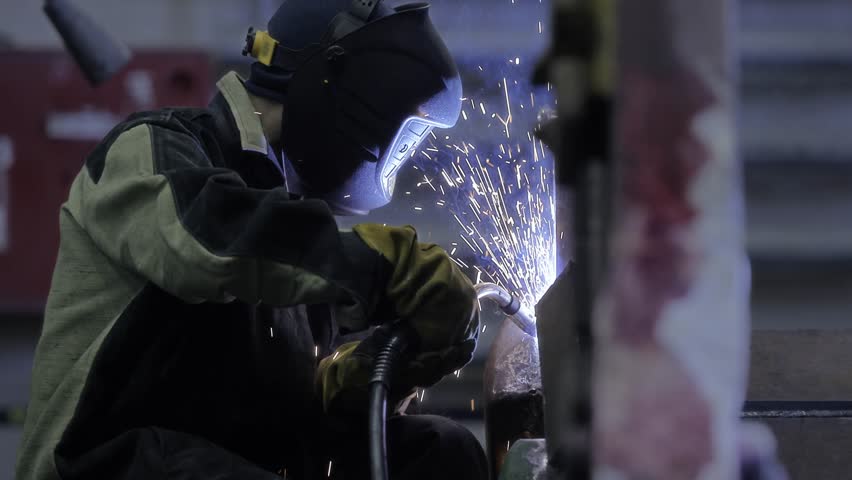 Professional worker fix industry truck. Factory industrial welder in workplace with spark.