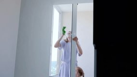 Woman happily cleans windows in an apartment, using a sponge and spray bottle. The scene highlights the joy of house cleaning and the fulfillment of domestic tasks - Powered by Shutterstock - Get 15% off with code: PIKWIZARD15