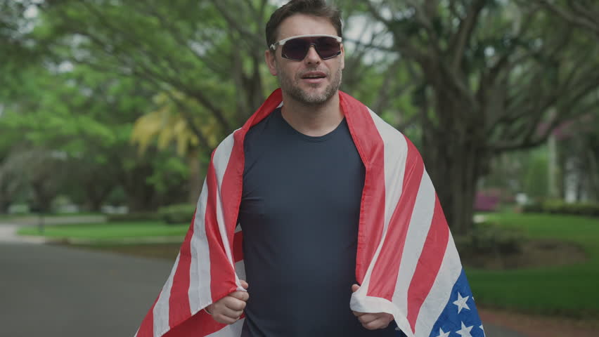 Runner wraps himself in United States flag and kisses it proudly after crossing finish line. Male athlete symbolizes victory, patriotism, and celebration of first place achievement. - Powered by Shutterstock - Get 15% off with code: PIKWIZARD15