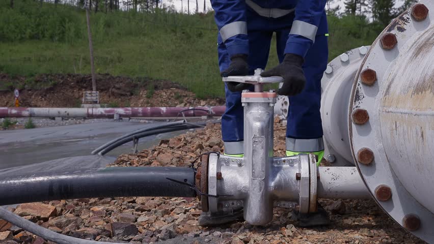 Engineer opens the shut-off valve of Industrial waste from copper and iron enrichment production, mining tailings storage facility.