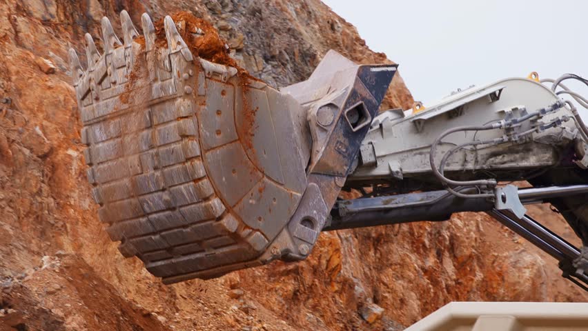 Excavator loads copper ore into big dump truck in open gold pit mine. Process gold mining industry workplace.