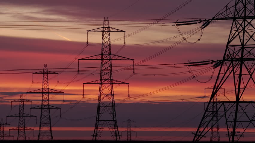 Silhouettes of Electricity Pylons Against a Fiery Sunrise Sky Over a Remote Moor Landscape