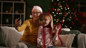 Grandmother and granddaughter wearing christmas decorations taking selfies and making video calls - Powered by Shutterstock - Get 15% off with code: PIKWIZARD15