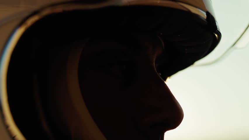 Car Driver Lowers Visor in Silhouette at Sunset After Race