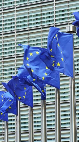 European Union Blue Flags and Berlaymont Building, Headquarters of the European Commission. City of Brussels, Belgium. Slow Motion. Vertical Video