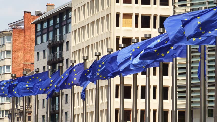 Row of European Union Blue Flags against Buildings in City of Brussels, Belgium. Slow Motion