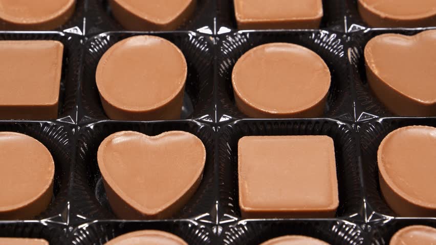 Chocolate candies in packaging. Valentines Day Gift. Candies are square, round and heart-shaped. Delicious chocolate candy with of different forms, including heart-shaped ones
