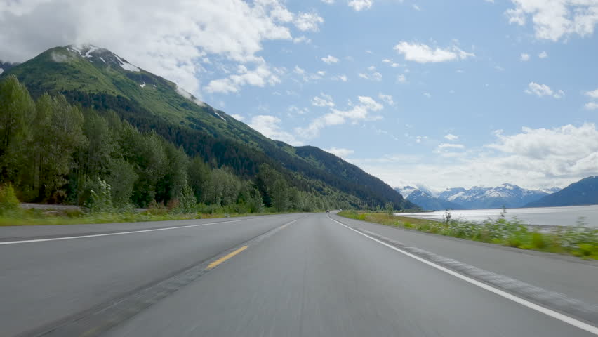 POV Driving a car on asphalt road in Alaska. Road toward Seward. Blue sky on sunny day
