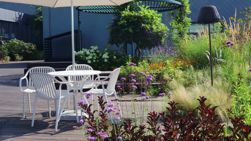 There are parasols and chairs in the urban garden created on the rooftop of a building in the city center