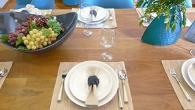 An elegant wooden dining table is beautifully set for a formal dinner party, featuring modern white tableware, placemats, and a centerpiece of fresh grapes. - Powered by Shutterstock - Get 15% off with code: PIKWIZARD15