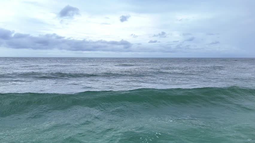 Ocean waves rolling under cloudy dramatic sky. Drone view