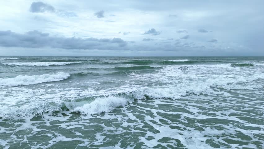 Strong ocean waves breaking under cloudy stormy sky. Drone video