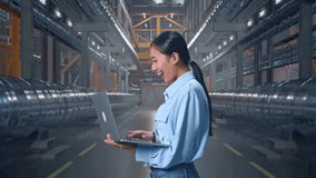 Side View Of An Asian Female Professional Worker Standing With Her Laptop In a In Big Warehouse Filled With Metal Pipes, She Raises Her Fist Up With Screaming Goal After Typed On The Laptop - Powered by Shutterstock - Get 15% off with code: PIKWIZARD15