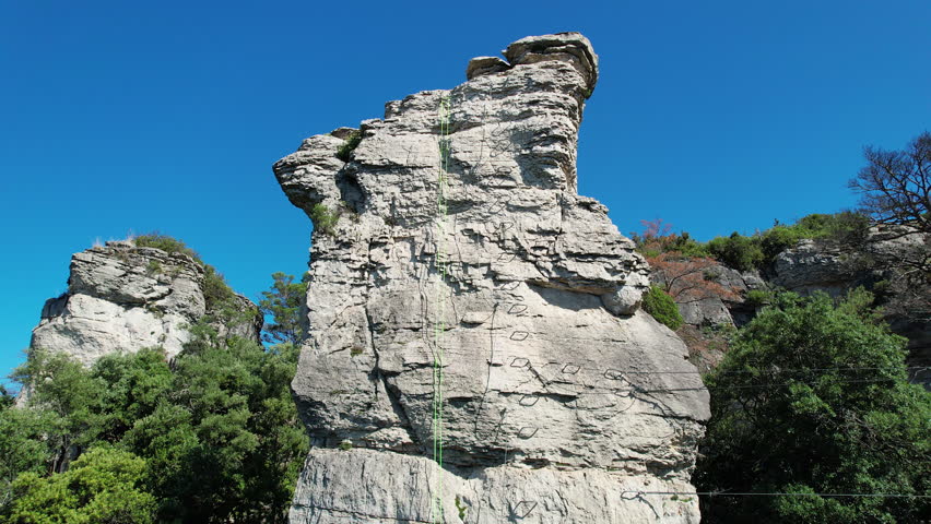 Tilt down aerial footage of a rock pillar on Via ferrata Patacons on sunny summer day. Mussara, Tarragona, Spain.
