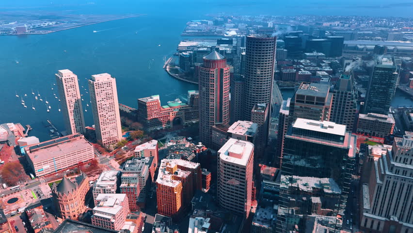 Flying high above the downtown of Boston, Massachusetts, USA. Approaching peaceful waterscape of the Charles River with multiple sailboats.