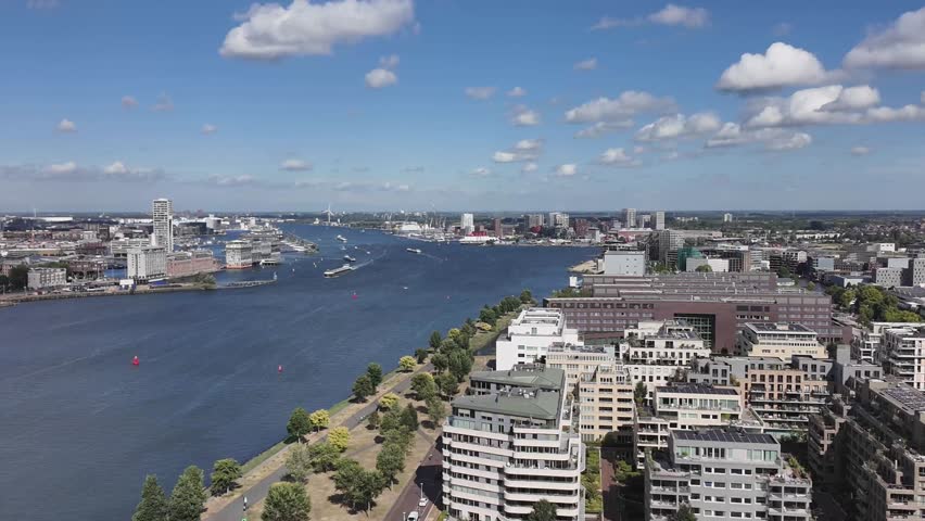 Aerial view of Amsterdam’s skyline over the IJ River at golden light, showcasing the Dutch capital’s waterways, architecture, and urban splendour