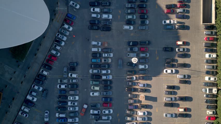 Top view zoom out car driving on parking place. Aerial view from above flying drone car moving and standing on parking lot in modern city. Car traffic and parking concept.High quality 4k footage