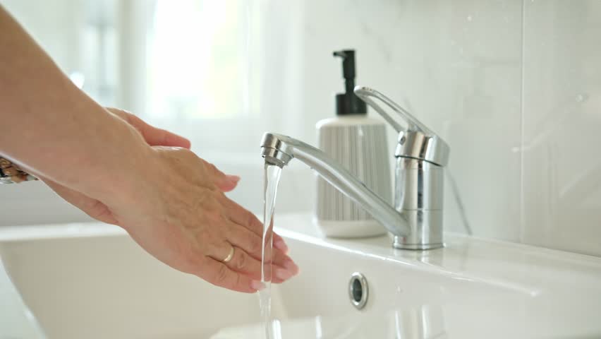 Woman Washing Hands Over A Sink In The Bathroom, Close-Up